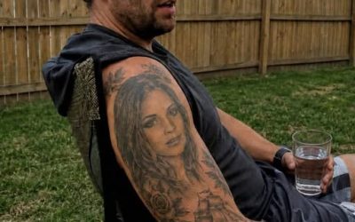 “Pensavo che il tatuaggio di mio marito raffigurasse una donna qualsiasi finché non l’ho incontrata dal vivo Dal primo giorno in cui ho conosciuto mio marito, ho notato che aveva un tatuaggio raffigurante il volto di una donna sulla spalla. Non un nome. Non un simbolo. Non un vago disegno artistico che potesse significare chissà cosa. Un ritratto completo. Una giovane donna con occhi dolci, capelli scuri e un’espressione quasi triste, come se qualcuno l’avesse colta nel bel mezzo di un segreto. All’inizio non ho chiesto. Avevamo appena iniziato a frequentarci ed ero troppo imbarazzata per parlarne. Non volevo sembrare gelosa o insicura per un tatuaggio che era lì da molto prima di me. Ma ogni volta che indossava una canottiera, o andavamo a nuotare, o si girava nel letto, eccola lì. Questa donna che non conoscevo, che mi fissava dalla pelle del mio ragazzo. Alla fine, quando la nostra relazione si è fatta più seria, ho finalmente trovato il coraggio di chiedere. “Chi è?” Lui a malapena guardò il tatuaggio prima di Scrollando le spalle. “Nessuno. Non preoccuparti.” Quella risposta avrebbe dovuto turbarmi di più, ma ero giovane, innamorata e non volevo assolutamente sembrare il tipo di fidanzata che crea drammi per niente. Così lasciai perdere. Poi ci siamo fidanzati. Una sera, mentre eravamo a letto, ho ripassato con il dito il contorno del tatuaggio e ho detto, scherzando a metà: “Okay, ci sposiamo. Finalmente puoi dirmi la verità. Chi è questa donna sconosciuta sulla tua spalla?” Ha riso, ma la sua risata sembrava forzata. Poi ha detto: “Non c’è niente di strano. Anni fa un mio amico stava imparando a fare tatuaggi realistici. Ha scaricato una foto a caso da internet e aveva bisogno di qualcuno su cui fare pratica. Gli ho prestato me.” Ricordo di averlo fissato, cercando di capire se quella fosse la spiegazione più stupida che avessi mai sentito o semplicemente il tipo di stupidaggine che un ragazzo giovane farebbe. Alla fine, gli ho creduto. Oppure Almeno, mi dicevo di sì. Dopo il matrimonio, però, il tatuaggio ha iniziato a darmi sempre più fastidio. Odiavo vedere il volto di un’altra donna sul corpo di mio marito. Odiavo il fatto che non avesse una vera spiegazione. Odiavo il fatto che ogni volta che ne parlavo, lui si comportasse come se fossi irragionevole. Alla fine, gli dissi che volevo che lo coprisse. Non che lo rimuovesse. Non che facesse un grande sacrificio. Solo che lo coprisse con qualcos’altro. Qualsiasi altra cosa. All’inizio, discusse. Poi disse di aver capito. Poi promise che avrebbe preso un appuntamento. Ma in qualche modo, c’era sempre una scusa per non farlo. Il suo tatuatore era fuori città. Non avevamo i soldi in quel momento. Non si sentiva bene. Era troppo impegnato con il lavoro. Voleva “pensare a quale disegno sarebbe stato meglio”. Passarono mesi. Poi anni. L’argomento si spense lentamente, non perché avessi smesso di interessarmi, ma perché mi ero stancata di sentirmi… Era come se stessi implorando mio marito di cancellare un’altra donna dalla sua pelle. Alla fine, mi ci ero semplicemente abituata. Fino alla settimana scorsa. Ero fuori a fare commissioni nella nostra città natale e mi sono fermata al panificio locale per un caffè. Era affollato e stavo quasi per voltarmi e andarmene, ma poi la donna in fila davanti a me ha girato leggermente la testa. E io mi sono bloccata. Mi si è gelato il sangue in tutto il corpo. Era lei. La donna del tatuaggio sulla spalla di mio marito. Ora era più grande, forse di dieci o quindici anni rispetto a quando aveva il tatuaggio, ma non avevo dubbi. Avevo fissato quel viso per tutta la durata del mio matrimonio. Conoscevo la forma dei suoi occhi. La curva della sua bocca. Il piccolo neo vicino alla mascella. Era lei. Le mie mani hanno iniziato a tremare così forte che ho quasi lasciato cadere il telefono. Per qualche minuto sono rimasta lì immobile, a guardarla ordinare il caffè come se non fosse il volto che aveva tormentato il mio matrimonio per anni. Poi, prima che potessi convincermi del contrario… Mi avvicinai a lei. “Mi scusi”, dissi, cercando di mantenere la voce calma. “Le sembrerà strano, ma conosce un uomo di nome…” E poi dissi il nome di mio marito. Il volto della donna cambiò all’istante. Tutto il colore le svanì. I suoi occhi si spalancarono, non per la confusione, ma per la paura. Fece un passo indietro.